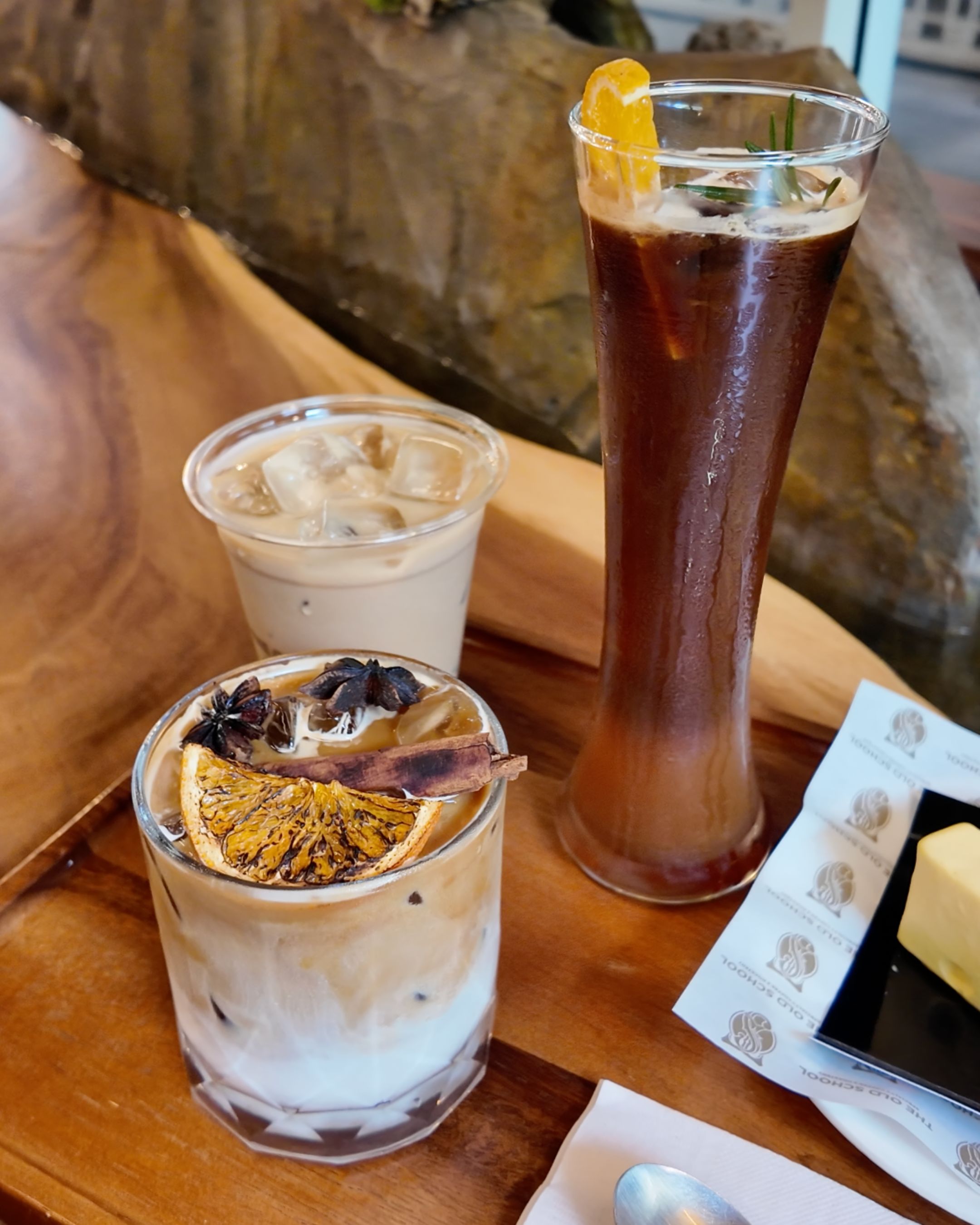 Explore a selection of refreshing drinks at The Old School Specialty Coffee Bangkok, including a creamy iced coffee and a tall dark iced beverage.