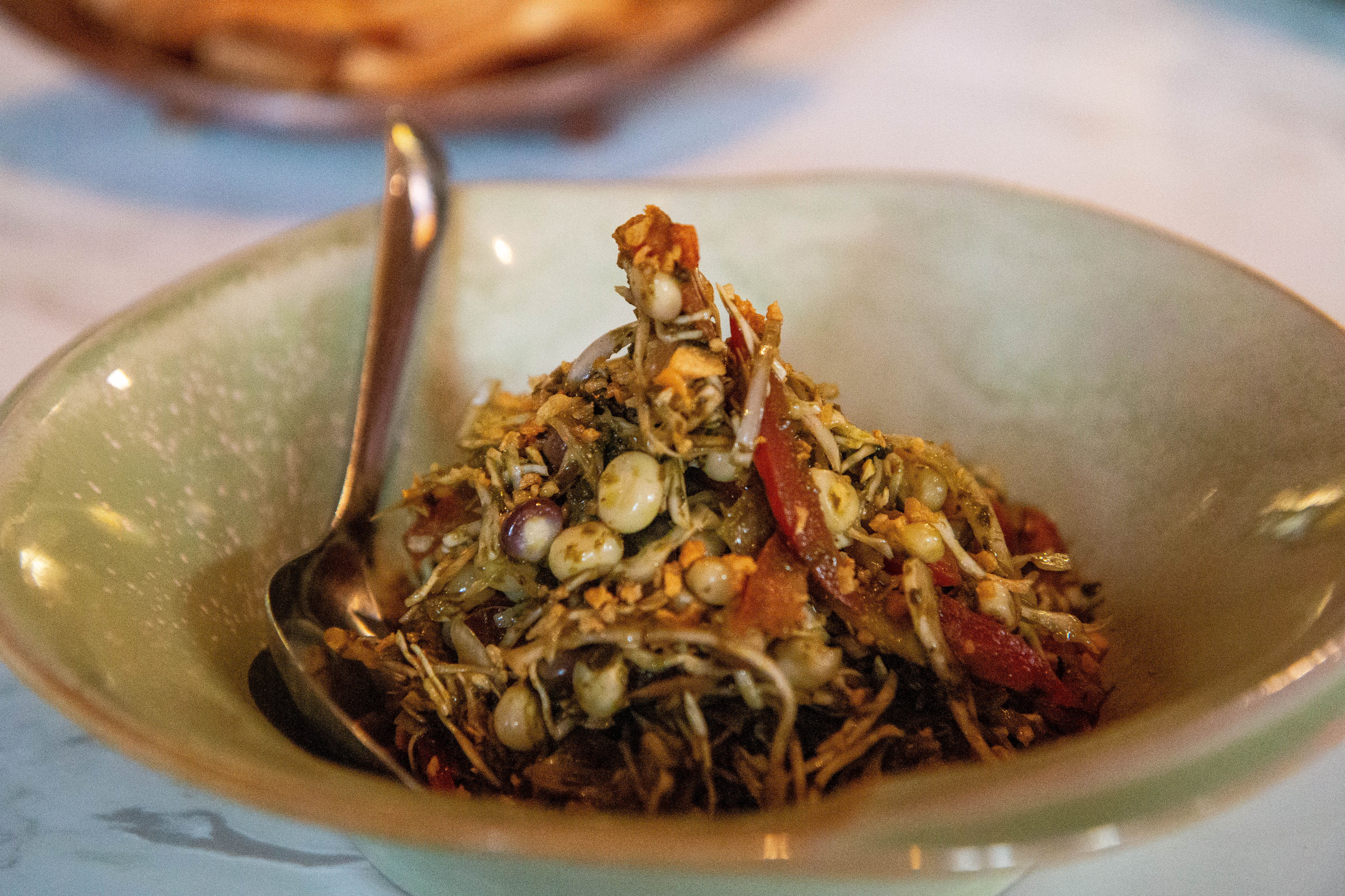 Authentic Shan Tea Leaf Salad with fermented tea leaves and sticky corn, a signature appetizer at Namsu Bangkok.