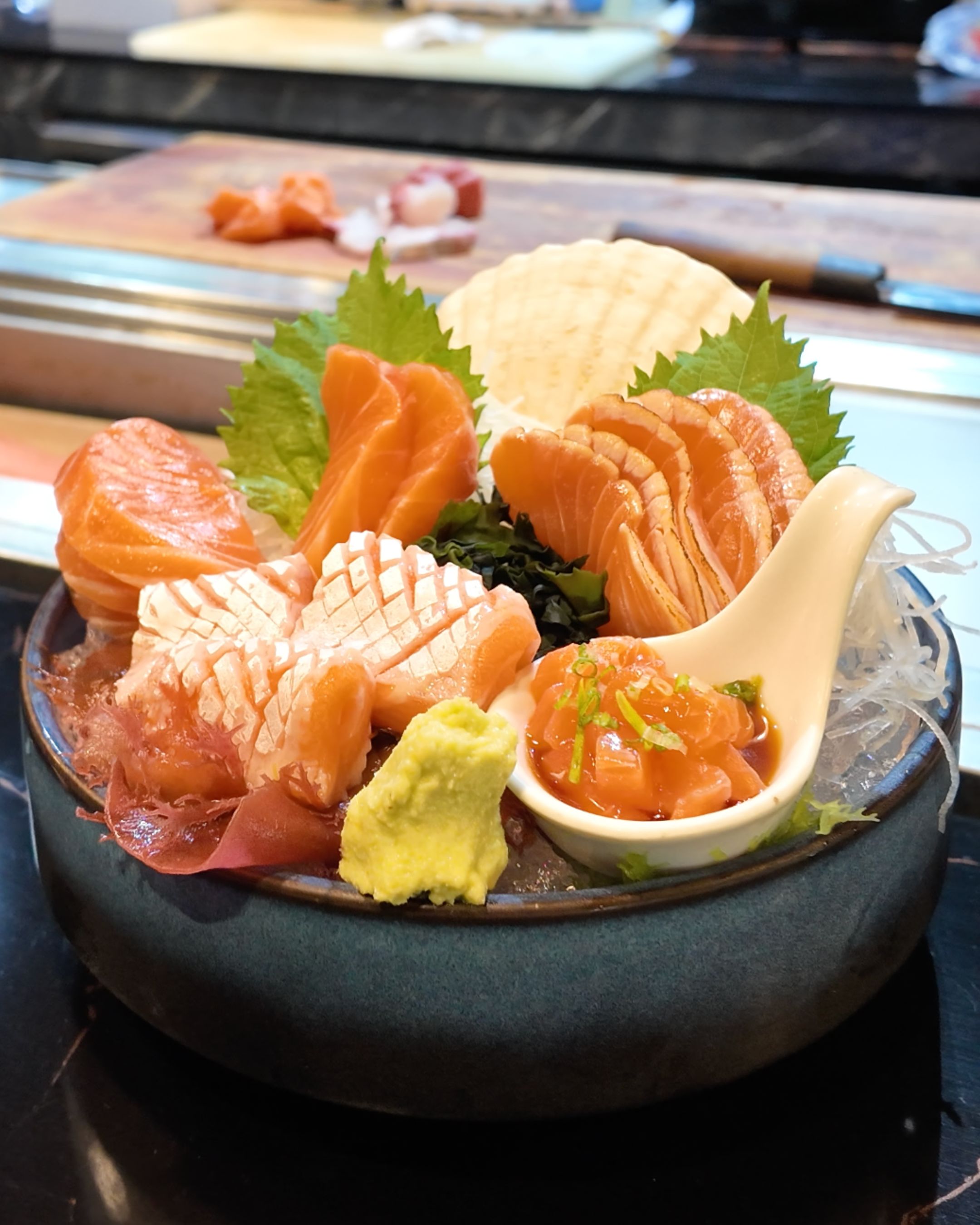 A colorful Japanese sashimi platter featuring fresh salmon slices, assorted seafood, salmon roe, wasabi and traditional garnishes at YAWA Bangkok.