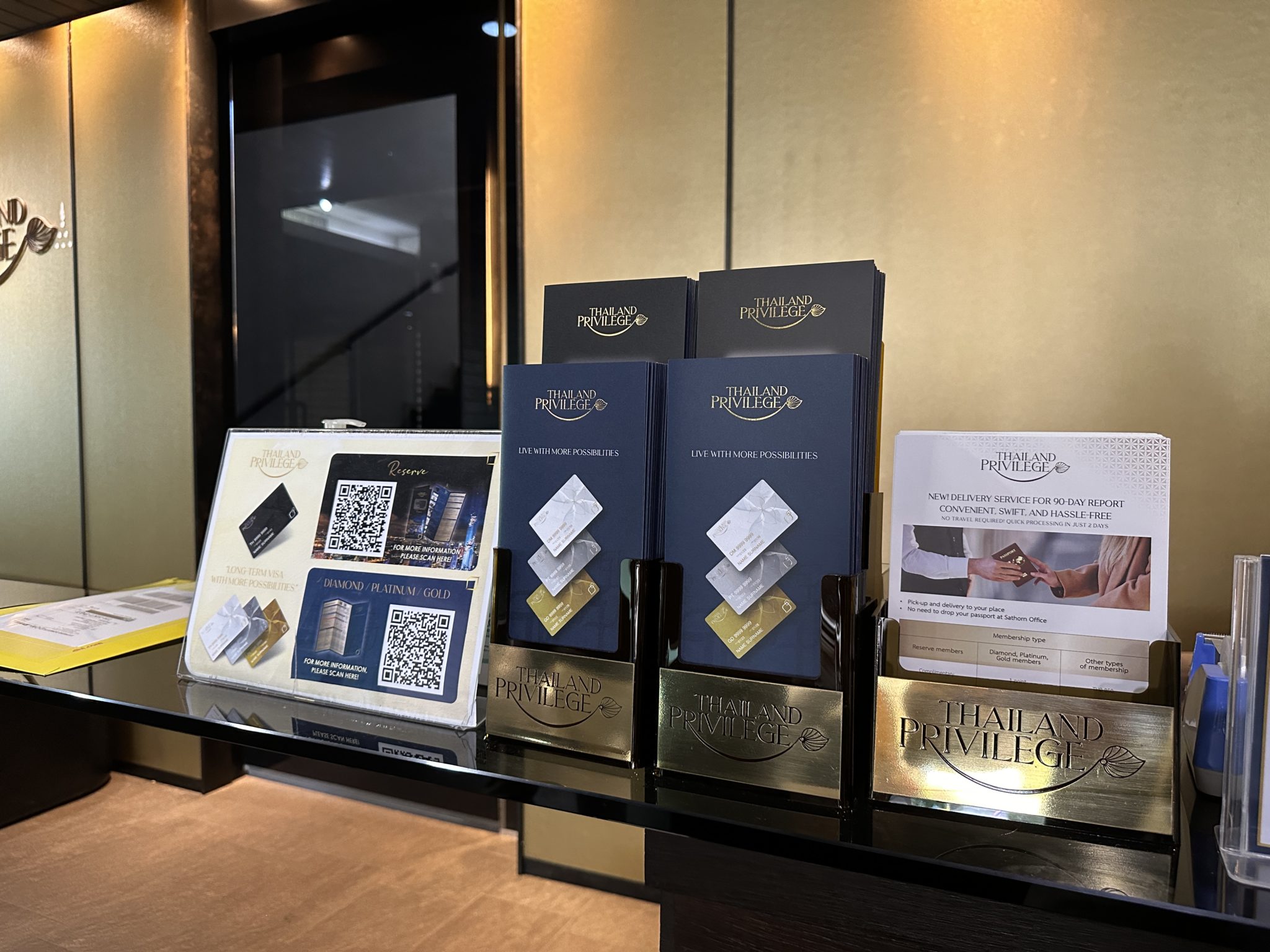 Thailand Privilege Card membership tier brochures and cards displayed at the Bangkok office counter