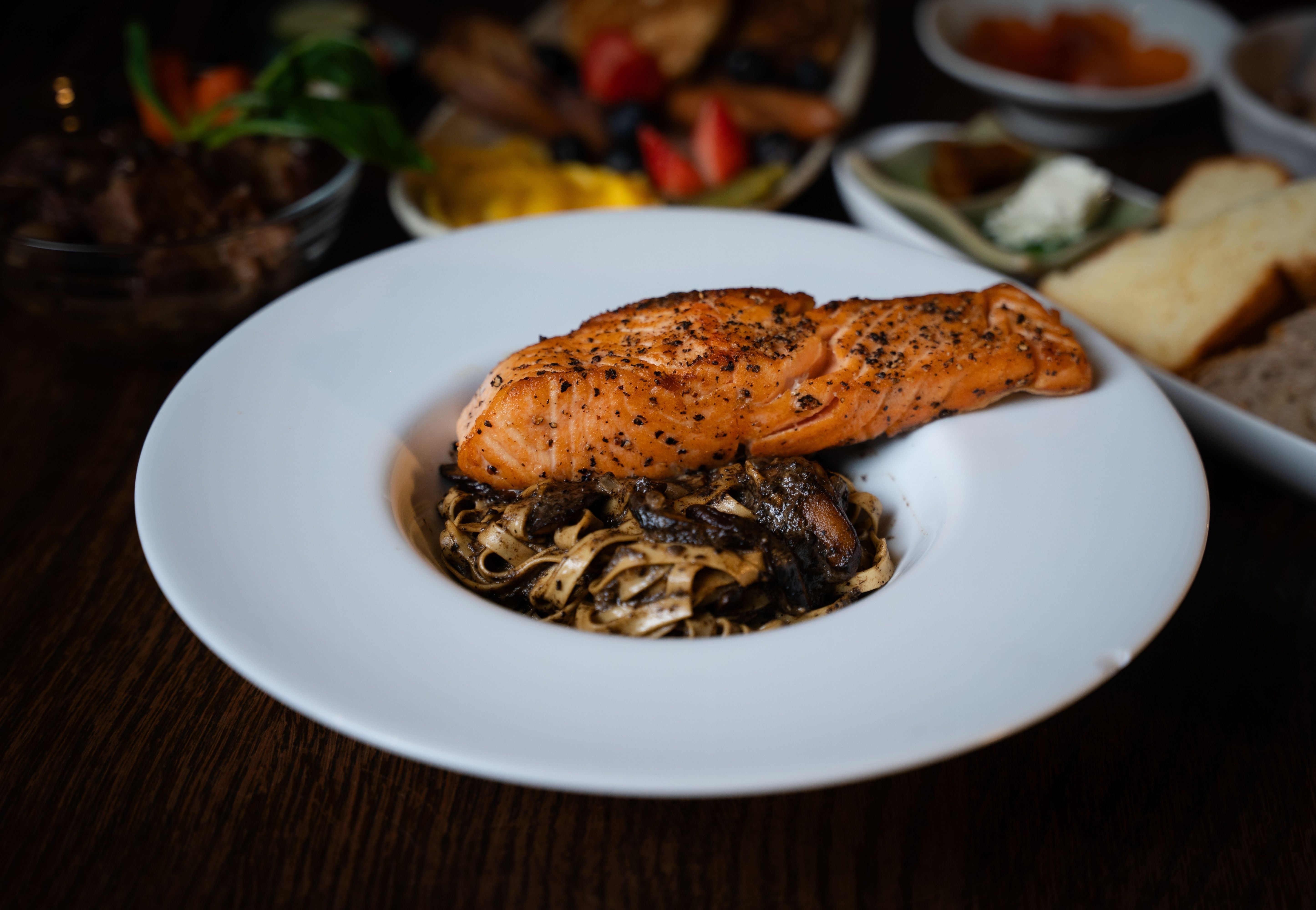 Grilled salmon fillet over dark mushroom tagliatelle pasta at Camelot Café Bangkok Charoen Krung 45