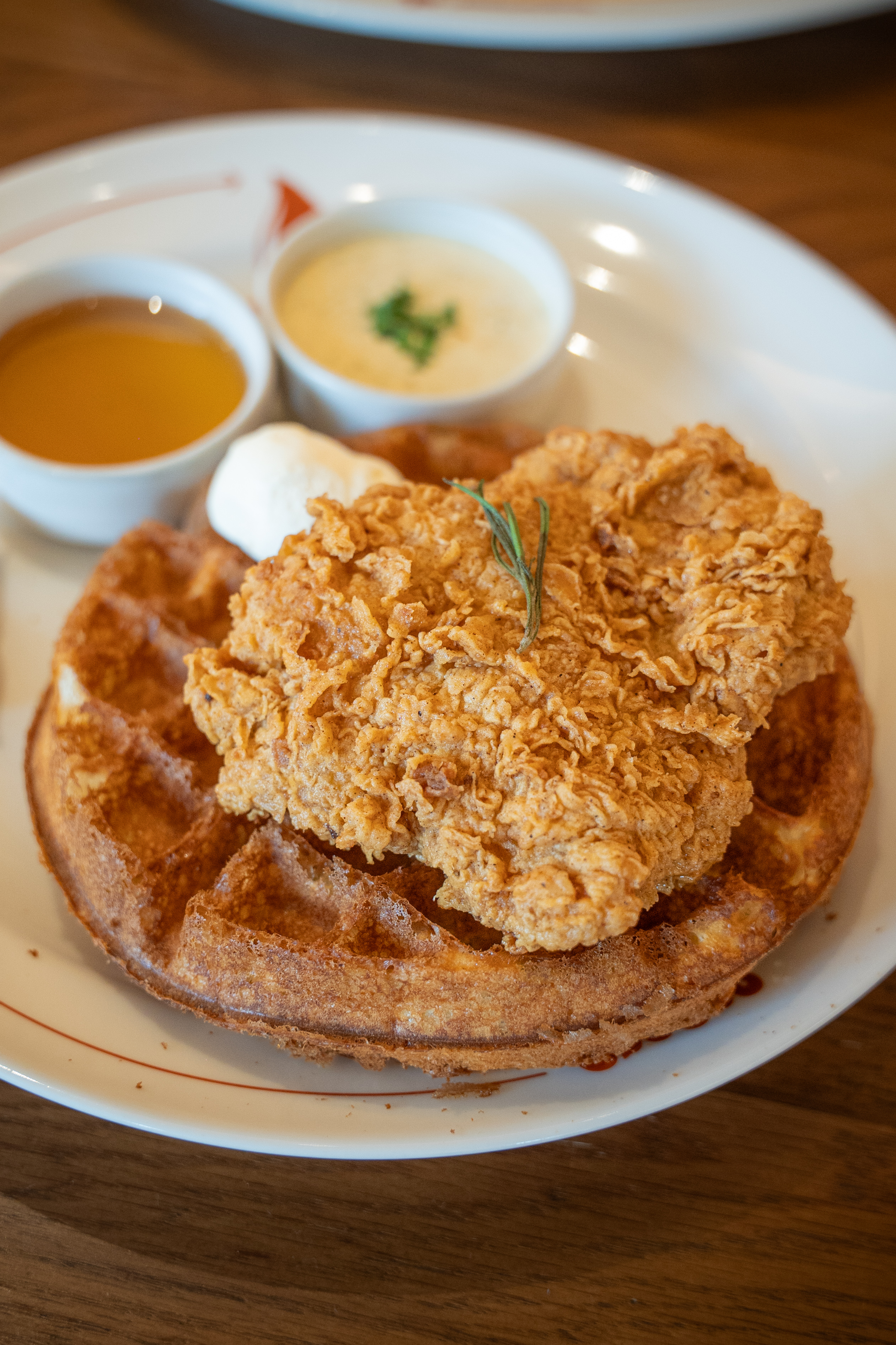 Golden crispy fried chicken served on a freshly made waffle, a delicious sweet and savory brunch combination at CouCou All Day Bangkok.