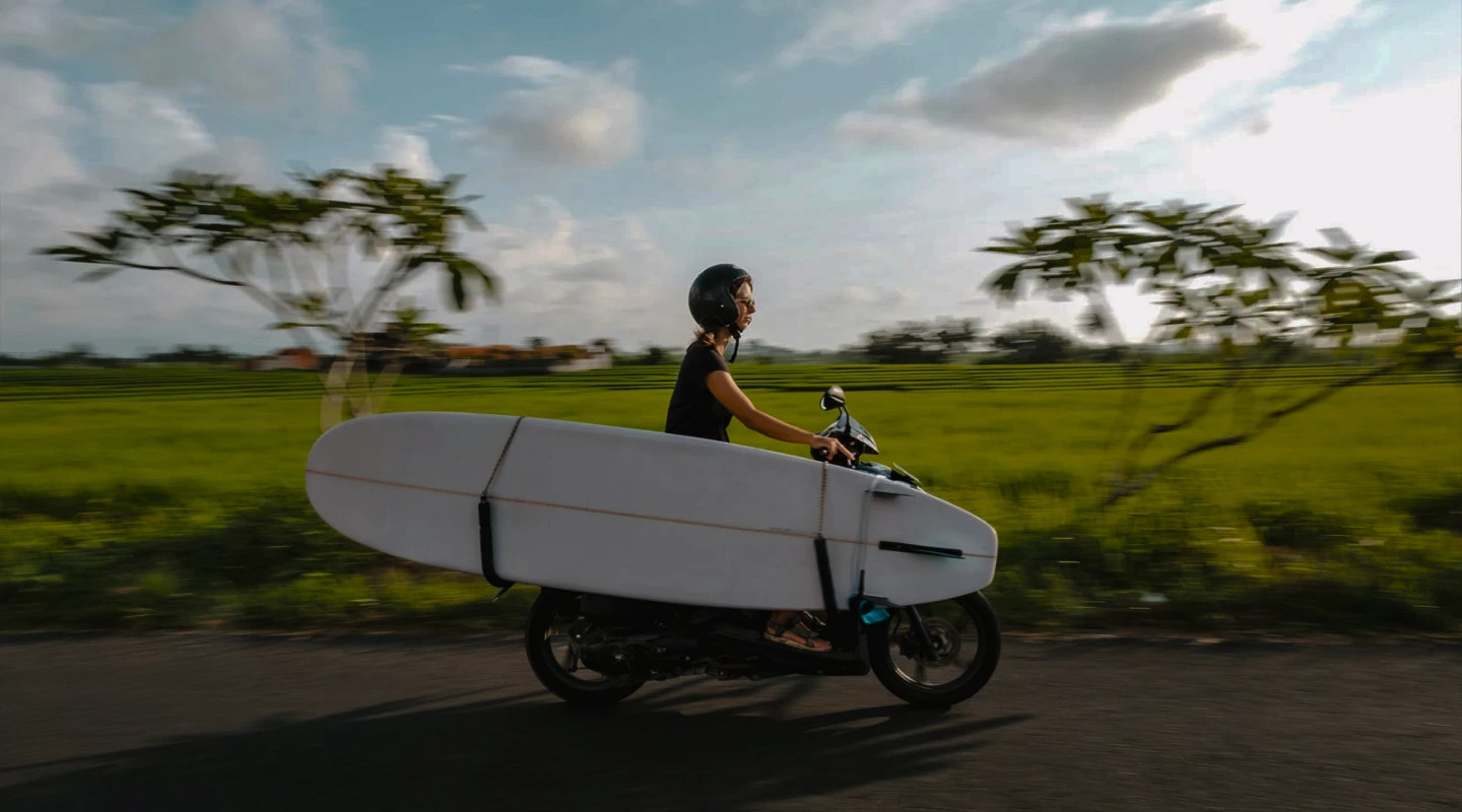 Bikago scooter with a surfboard on a country road