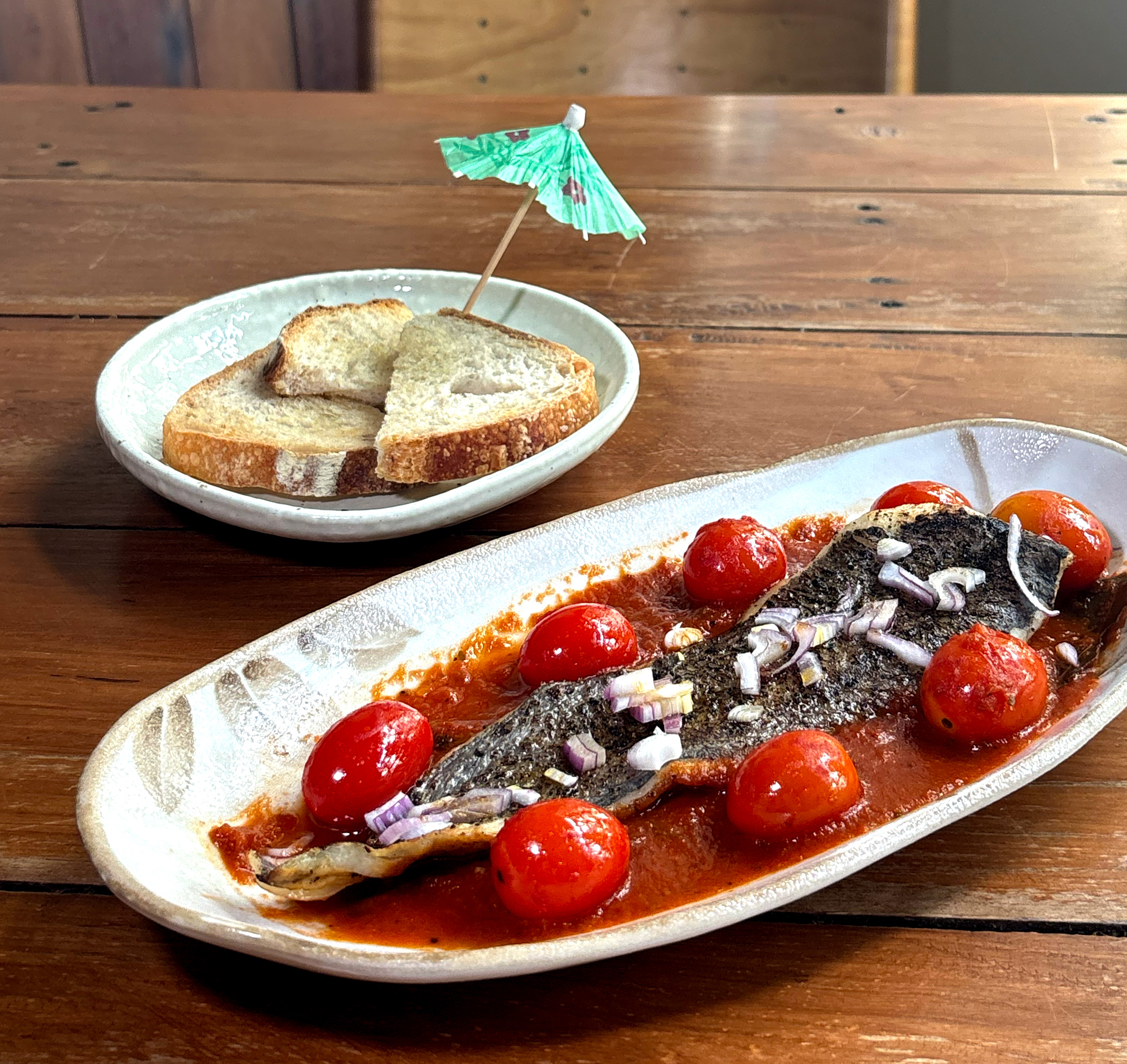 Crispy-skin grilled fish with cherry tomatoes and toast at Mad Moa, a Bangkok social restaurant