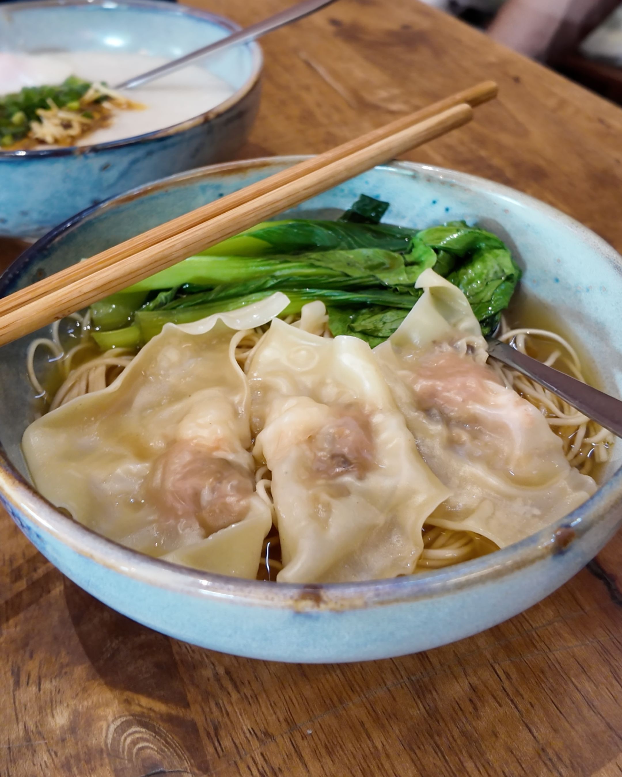 A delicious bowl of wonton noodle soup featuring tender dumplings, fresh green vegetables and a savory broth inspired by Thai-Chinese cuisine.