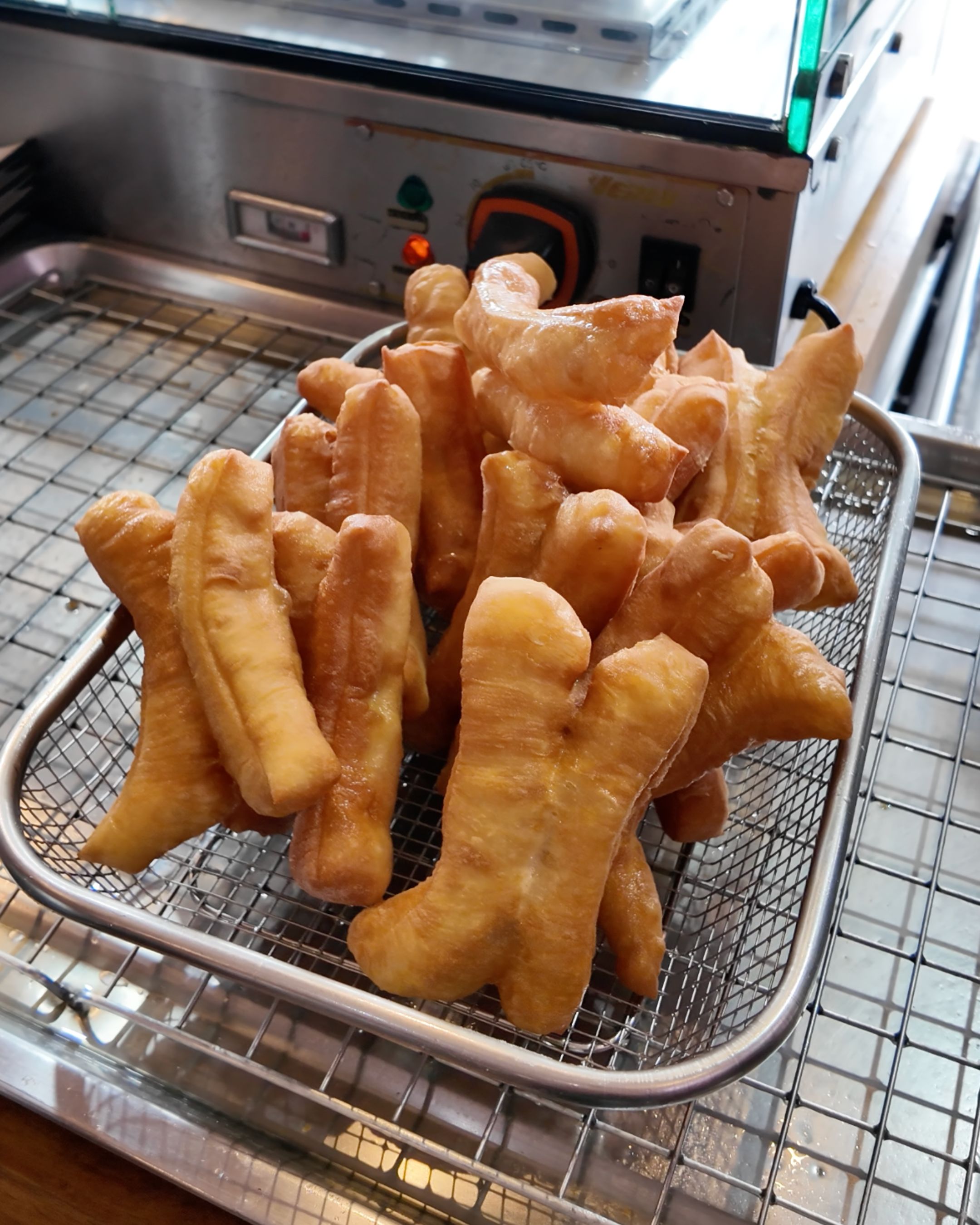 Golden and crispy Thai fried dough sticks, known as Pa Thong Ko, a popular breakfast specialty often enjoyed alongside traditional rice porridge.