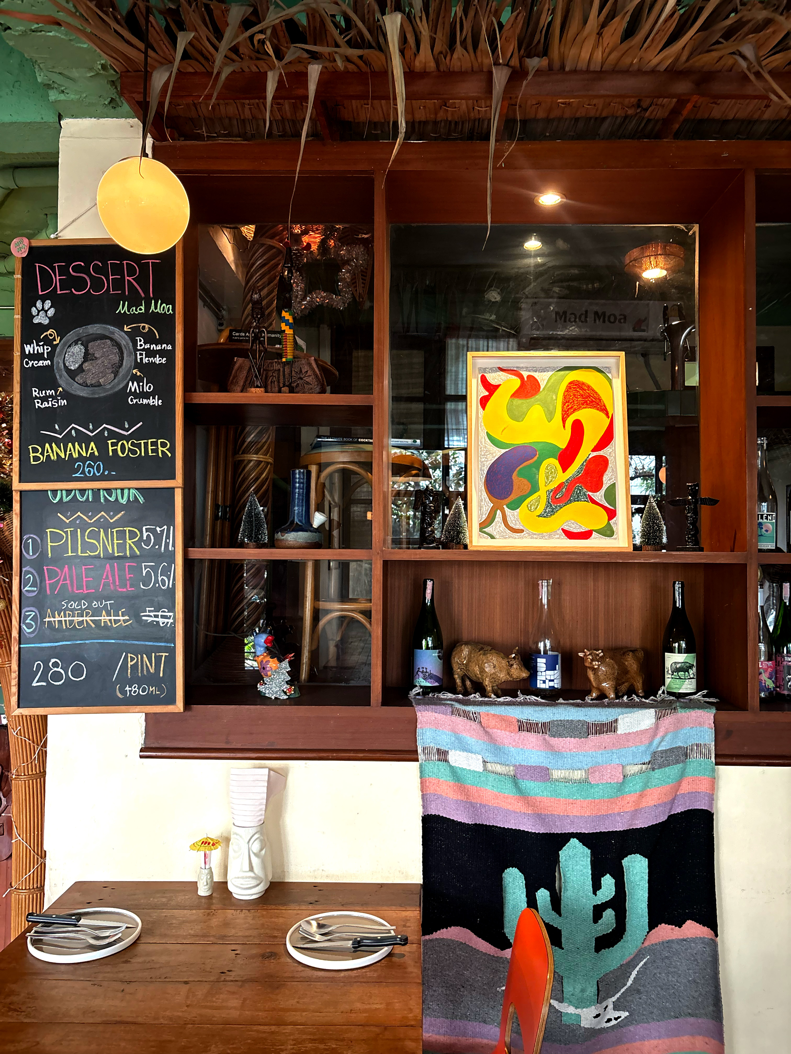 Tiki-style interior with dessert chalkboard and beach decor at Mad Moa restaurant in Bangkok