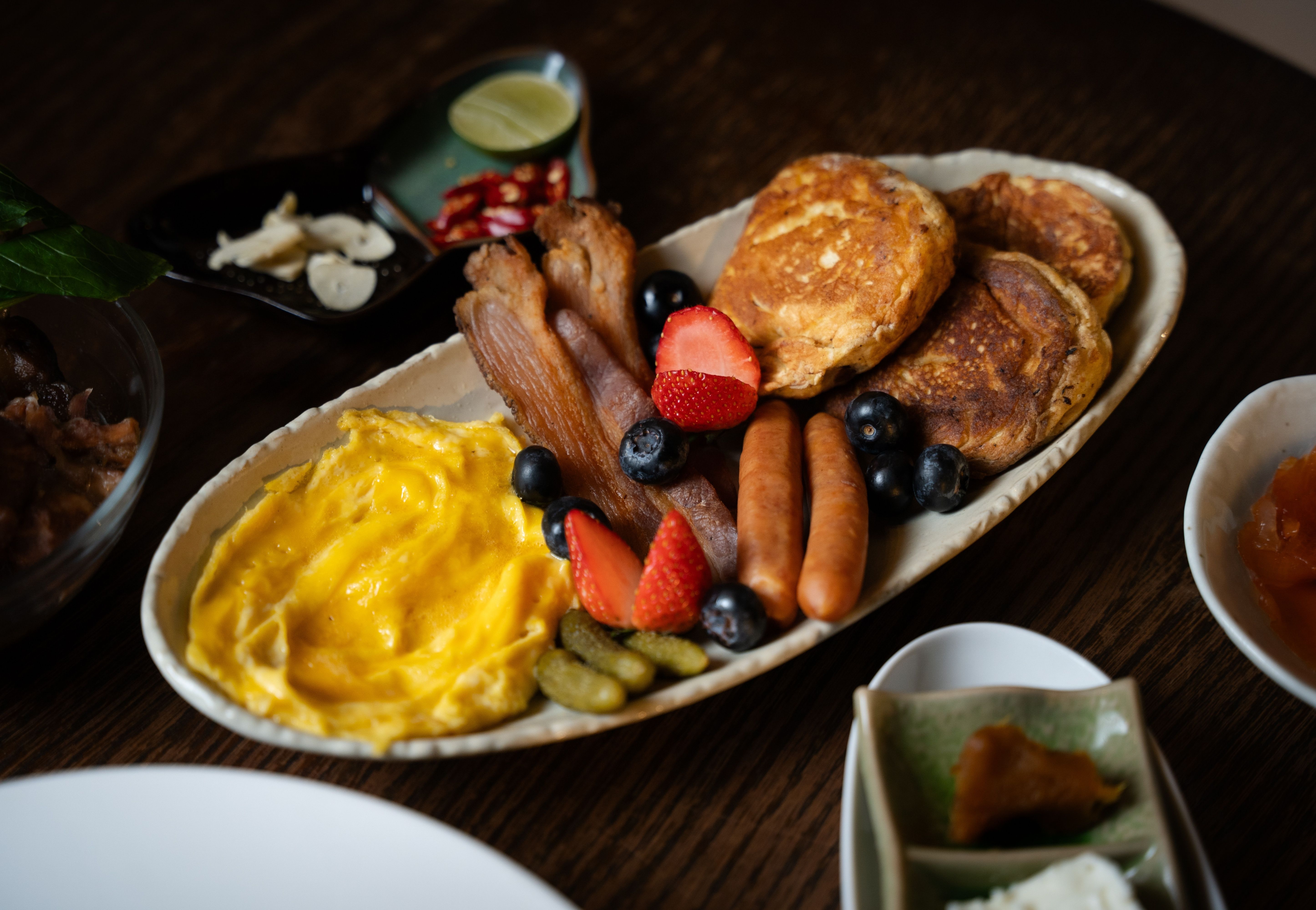 Brunch platter with scrambled eggs, pancakes, sausages, and berries at Camelot Café Bangkok
