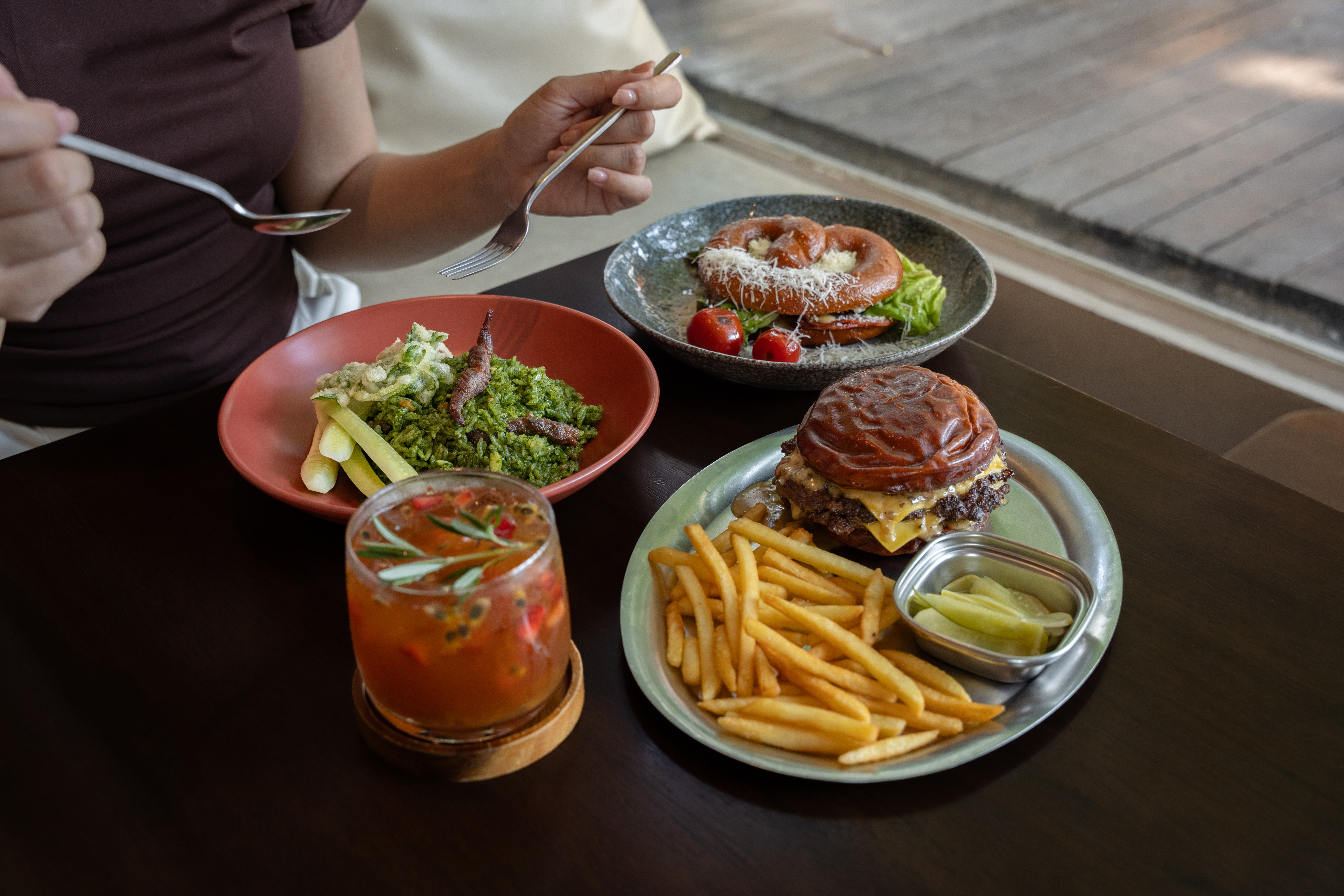 Bloom Neighborhood Dining Rama 9 bright indoor seating area with wooden furniture, large glass windows and natural light, homey café Bangkok