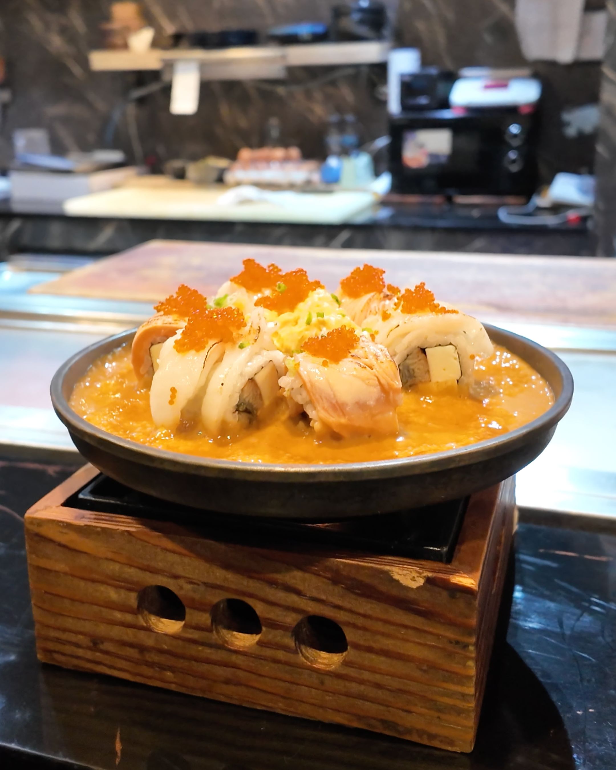 A beautifully presented Japanese dish featuring sushi rolls topped with vibrant orange fish roe and served in a rich, creamy sauce at YAWA Modern Japanese Cuisine.