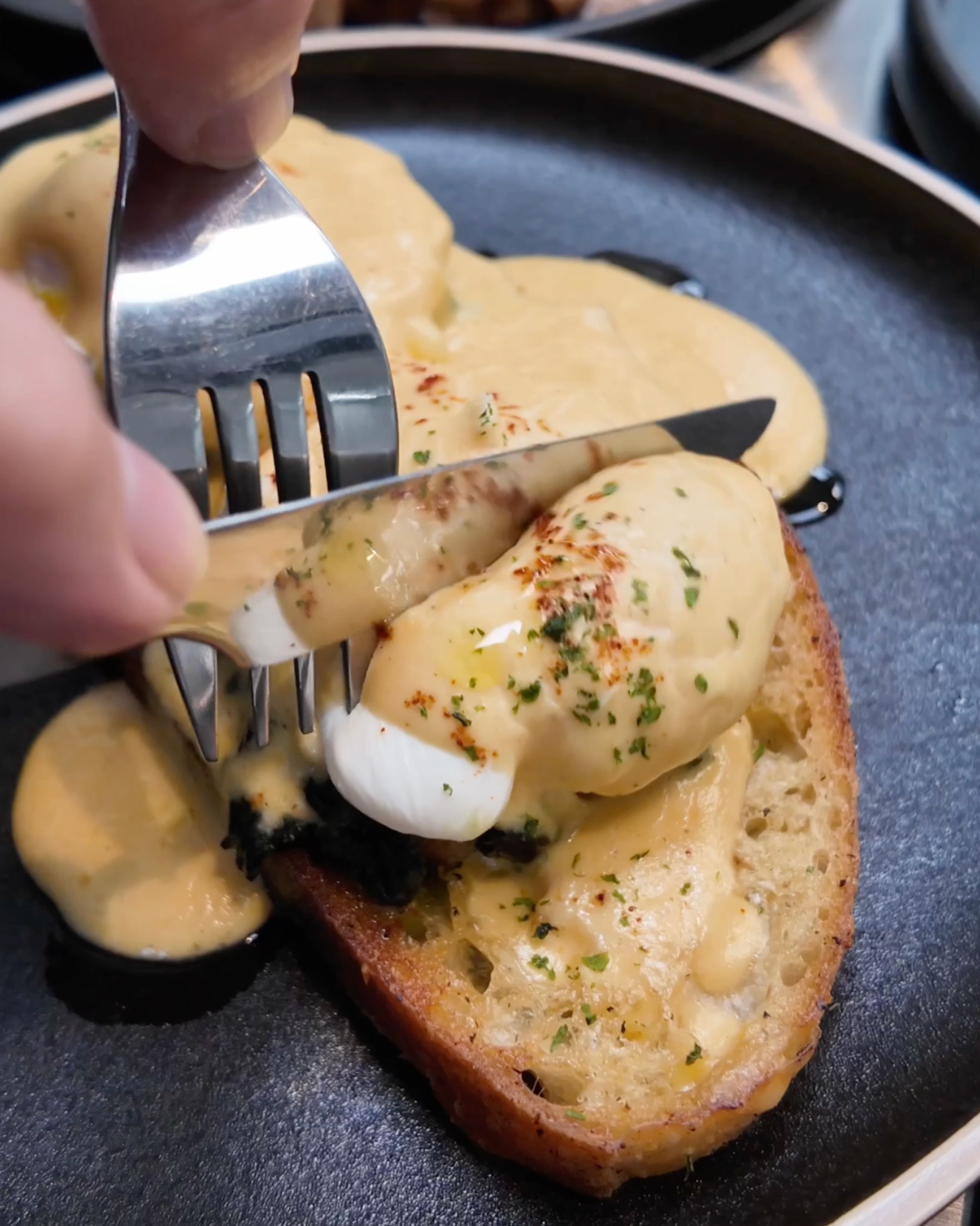 A delicious eggs Benedict dish served on toasted bread, topped with creamy hollandaise sauce and fresh herbs at JUNE. Cafe Bangkok.