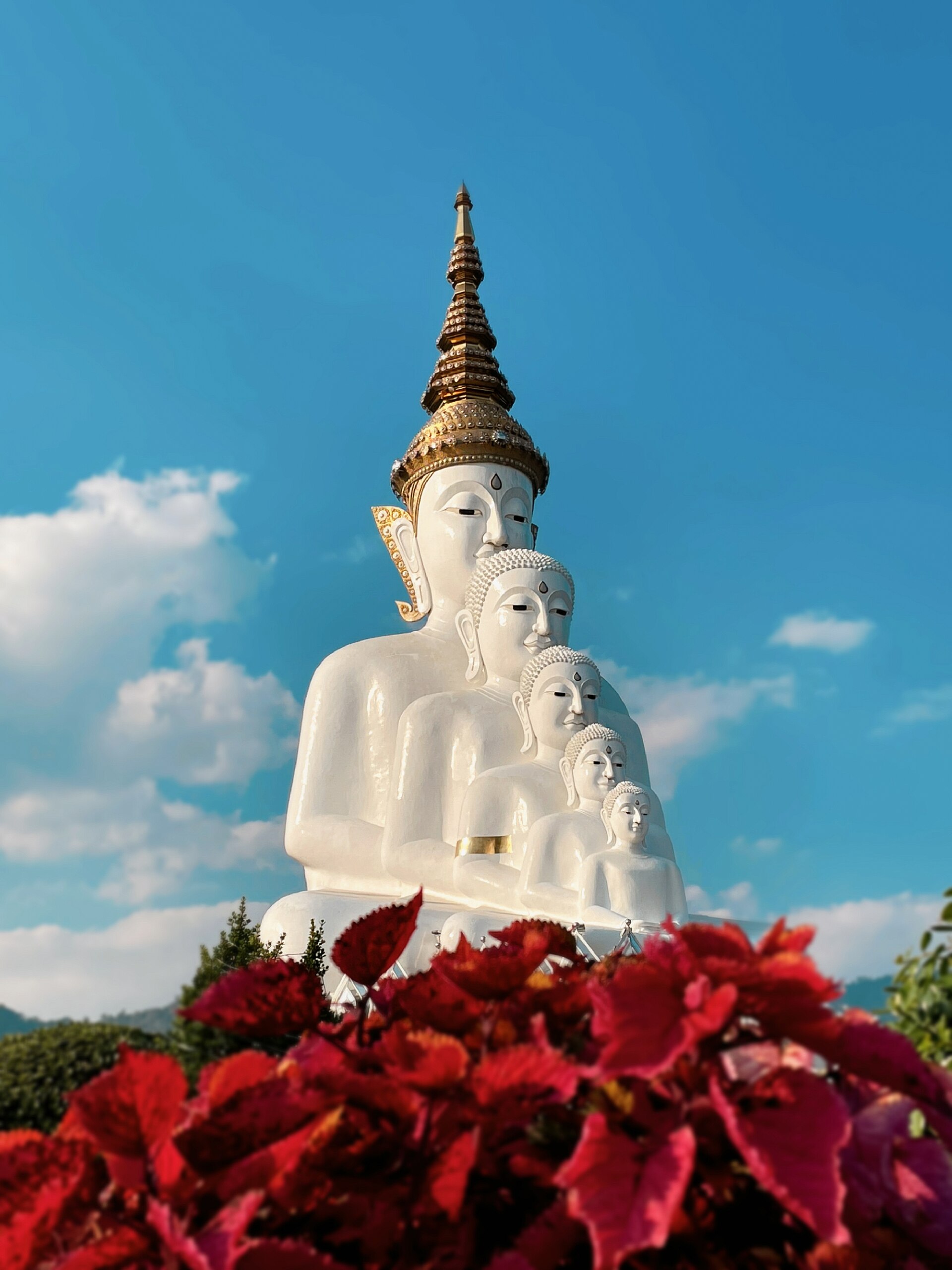 White Buddha images against a blue sky at Wat Pha Son Kaew
